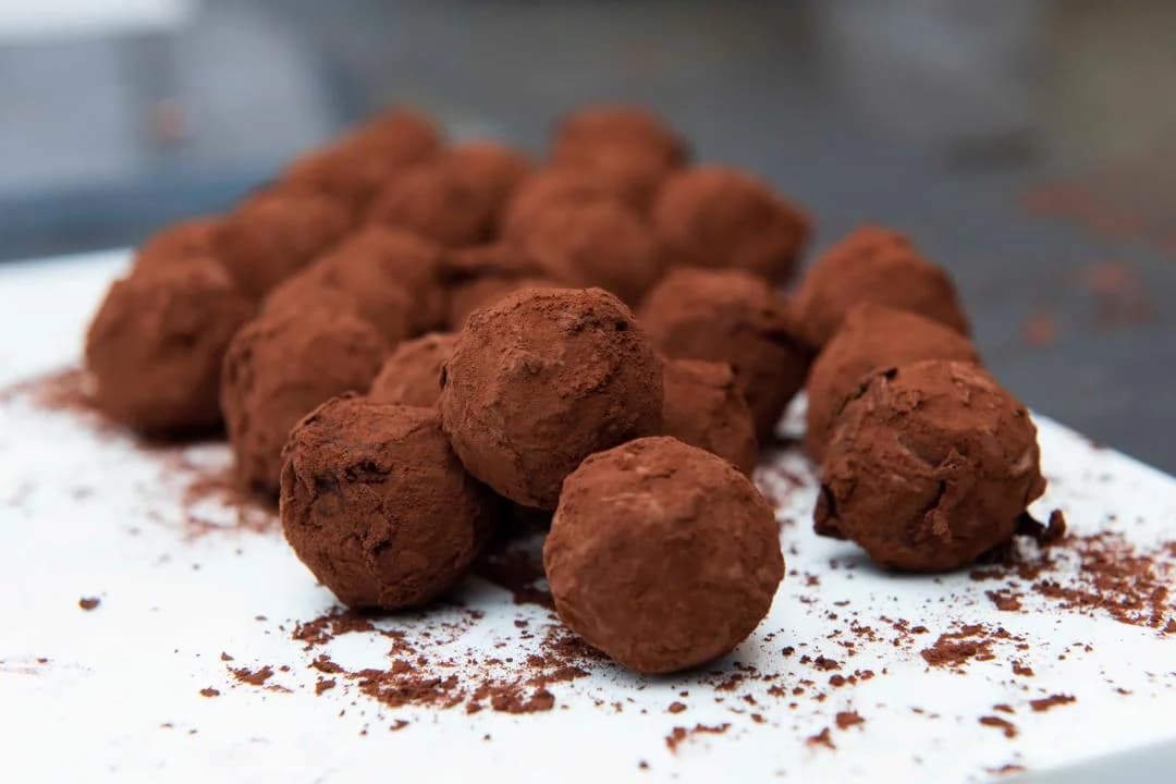 Cocoa-dusted chocolate truffles on a white surface