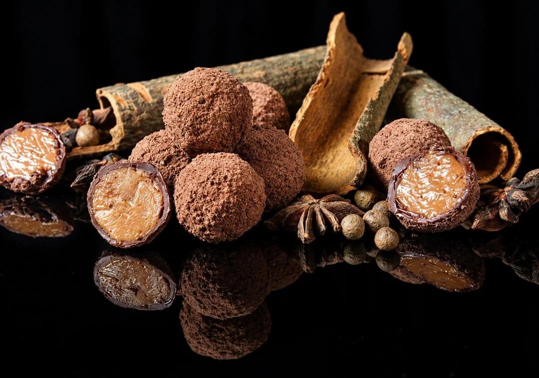Cocoa-dusted truffles, two cut open to show a soft caramel centre, with cinnamon bark, star anise and allspice
